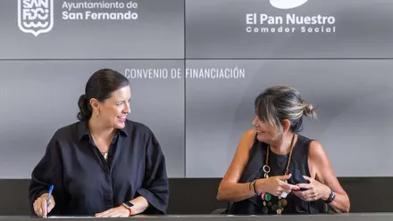 Dos mujeres, la alcaldesa de San Fernando y la representante de Cáritas, sentadas y firmando el convenio con la ciudad.