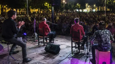 Grupo tocando flamenco ante un numeroso público.