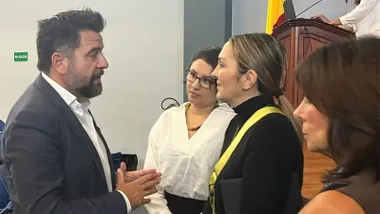 Fran González, delegado del Estado en la Zona Franca de Cádiz, conversa con la ministra de Ambiente y Energía de Costa Rica, Mónica Navarro del Valle, en un encuentro institucional celebrado durante la Joint International Staff Week. Ambos aparecen de pie dialogando en una sala de conferencias mientras se desarrolla el evento al fondo.