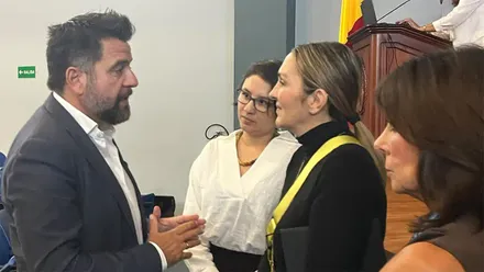 Fran González, delegado del Estado en la Zona Franca de Cádiz, conversa con la ministra de Ambiente y Energía de Costa Rica, Mónica Navarro del Valle, en un encuentro institucional celebrado durante la Joint International Staff Week. Ambos aparecen de pie dialogando en una sala de conferencias mientras se desarrolla el evento al fondo.