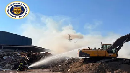Excavadora y bombero en el centro de reciclaje.
