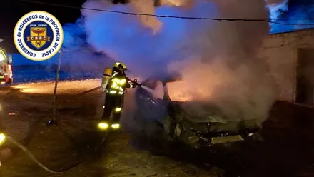 Bombero en tarea de extinción de un incendio. Es de noche.
