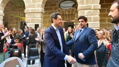 Jorge Vázquez saluda al presidente andaluz, Juanma Moreno, durante un acto institucional con público asistente.