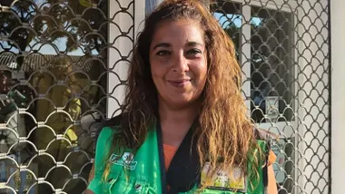 Chica del ONCE con su chalequillo característico en verde y letras amarillas.