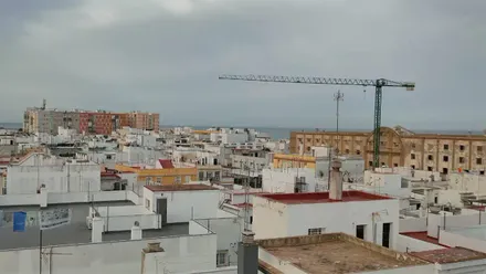Cielos nublados sobre el Campo del Sur de Cádiz, con el edificio de Valcarcel y la grúa de sus obras en primer término.