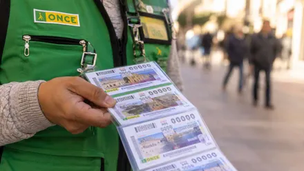 Persona trabajadora de la ONCE con cupones en la mano y el típico chalequillo verde.