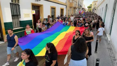 Personas paseando la bandera multicolor del Orgullo por Puerto Real.