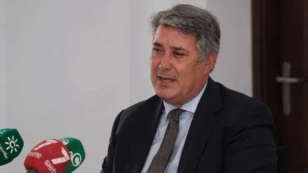 Imagen de Ignacio Romaní en una rueda de prensa, se ven los micrófonos, en rojo y verde, de los medios.
