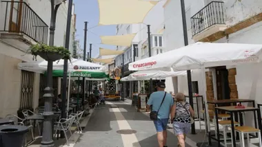 Calle comercial de Rota con toldos blancos protegiendo contra el sol.