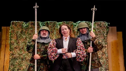 Dos soldados escoltando a una mujer en una obra de teatro.