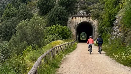 Dos ciclistas por un camino para entrar en un túnel de la Vía Verde.