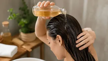 Mujer esparce agua con vinagre en su melena negra.