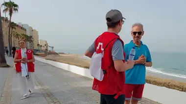 Voluntarios de Cruz Roja Cádiz repartiendo botellas de agua e informando a trabajadores y viandantes en la avenida Manuel de la Pinta, junto al Puente de la Constitución de 1812, durante la acción de sensibilización frente al calor extremo, una iniciativa que también se desarrollará en otras localidades de la provincia.
