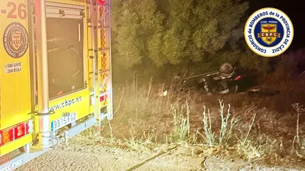 Accidente en Jimena, coche negro volcado y camión de bomberos.