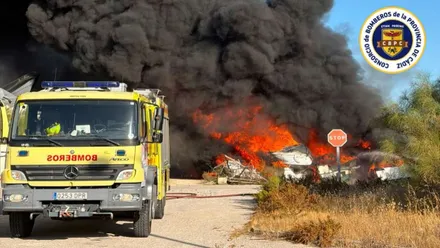 Masa de pasto ardiendo y un camión de bomberos en el trabajo de sofocar el incendio.