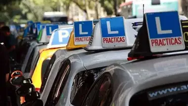 Coches de varias autoescuelas en fila con la L sobre el techo.