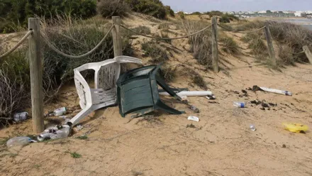 Restos de mobiliario de plástico y basura en la playa.