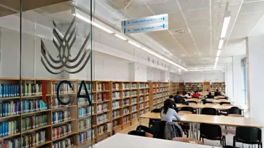 Puerta de cristal de la UCA de acceso a la sala de estudios con estudiantes en su interior.