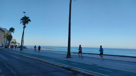 Paseo de Cádiz con el cielo despejado y personas caminando o haciendo footing.