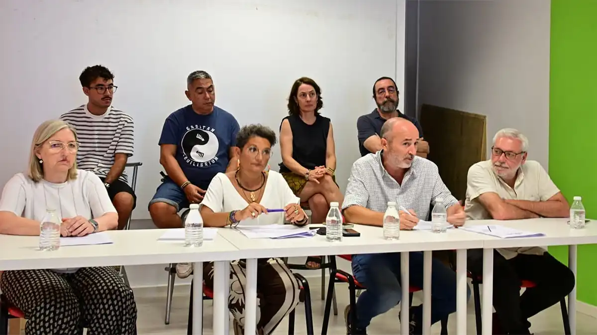 Ocho integrantes del grupo promotor, formado por representantes de partidos y colectivos de izquierda, participan en una rueda de prensa sentados tras una mesa con documentos y botellas de agua. La comparecencia se celebra en una sala de paredes blancas para presentar la campaña de recogida de firmas destinada a impulsar una consulta popular sobre las viviendas de uso turístico en Cádiz.