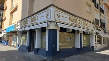 Fachada en esquina del local situado en Zurbarán 1. Un gran rótulo blanco con letras doradas recorre la parte superior de las dos fachadas, sobre los escaparates y los toldos.