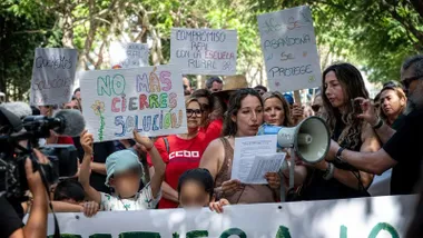 Madre con un altavoz reclamando mejoras en los colegios.