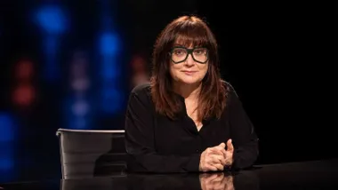 La cineasta Isabel Coiet en un plató de televisión con fondo oscuro y difuminado.
