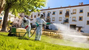 Dos operarios con epi fumigan contra los mosquitos.