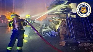 Bomberos vierten agua con sus mangueras sobre una estructura en llamas.