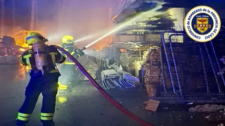 Bomberos vierten agua con sus mangueras sobre una estructura en llamas.