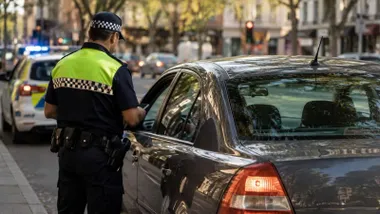 Agente de la Policía Local junto a un automóvil al que multa.