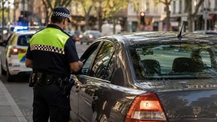 Agente de la Policía Local junto a un automóvil al que multa.