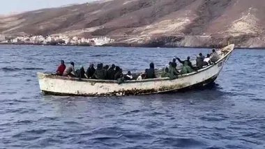 Una embarcación rústica con inmigrante ilegales en su interior llegando a tierra.