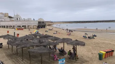 Decenas de personas están en la playa de la Caleta de Cádiz en una mañana gris y fresca