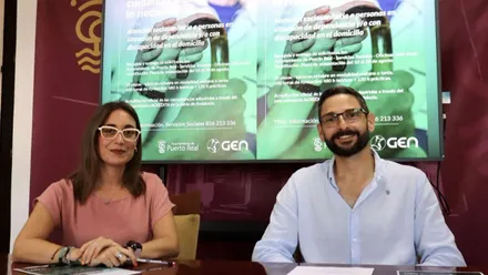 Lorena Díaz y José Alfaro presentando las bases de la oferta de curos, están sentados delante de una pantalla de televisión.