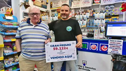 Dos personas sostienen un cartel con el premio logrado.