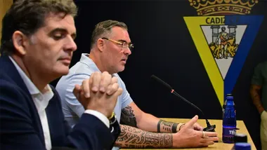 Rafael Contreras aparece en primer término, con las manos entrelazadas, mientras al fondo Christian Septien interviene ante el micrófono durante la comparecencia, con el escudo del Cádiz CF detrás de ambos.
