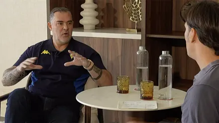 Christian Septien, presidente del Cádiz CF, sentado frente a José Grima, director de Comunicación del club, durante una entrevista en un salón. Septien gesticula mientras explica el proyecto del Cádiz CF y la futura ampliación de capital anunciada entonces y activada ahora por la entidad.