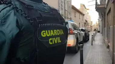Vehículo de la Guardia Civil y agente en una calle.