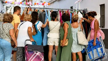 Mujeres viendo ropa en un perchero de una tienda en Rota dentro de Noche ComerciArte.