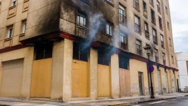 Edificio donde se produjo el incendio, hay humo que sale por las ventanas de la planta baja.