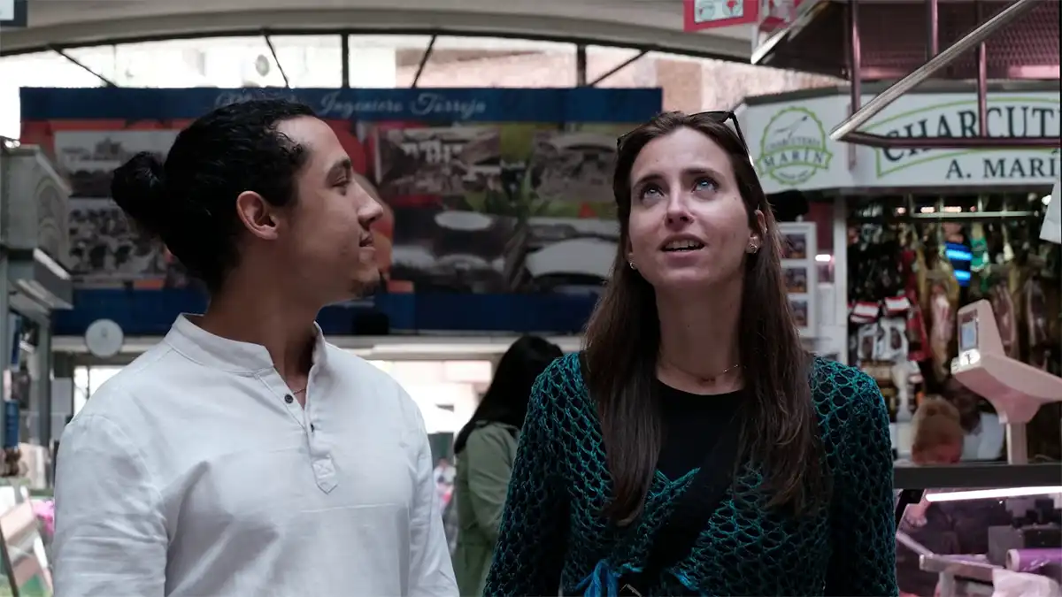 Un hombre y una mujer conversan en el interior de un mercado en una escena del documental Ideología, acero y hormigón: Manuel Sánchez Arcas.