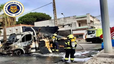Furgoneta incendiada y bomberos trabajando en el fuego.