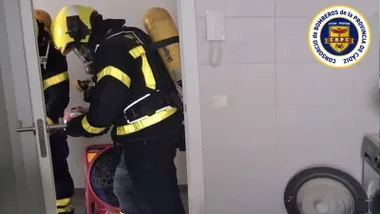 Un bombero con equipo de respiración en una cocina con azulejos blancos.