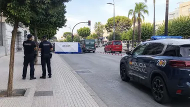 Dos policías nacionales junto a un vehículo en la calle Sevilla de Jerez que está acordonada.
