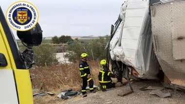 Dos bomberos tratan de sacar al conductor del camión.