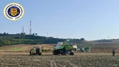 Bomberos en medio de un campo junto a una cosechadora.