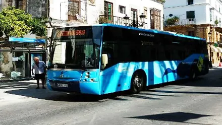 Un autobús de El Puerto, en color celeste, en una parada.