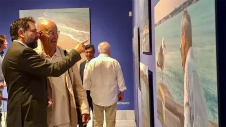 Fran González y Pablo Juliá observan varias obras sobre el mar expuestas en una sala de la Casa de Iberoamérica de Cádiz.