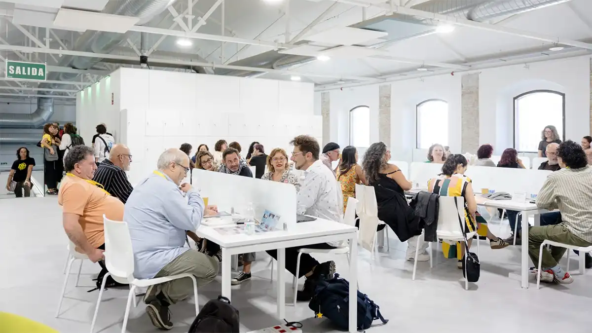 Varias personas conversan en grupos alrededor de mesas durante un encuentro profesional de Ultramarinos en un amplio espacio de los Antiguos Depósitos de Tabacalera de Cádiz.